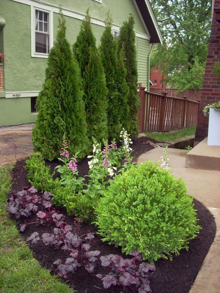 a green house with landscaping in the front yard