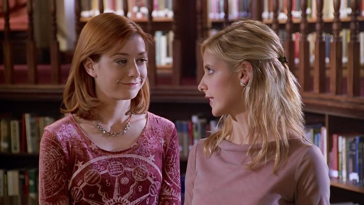 two young women standing in front of bookshelves