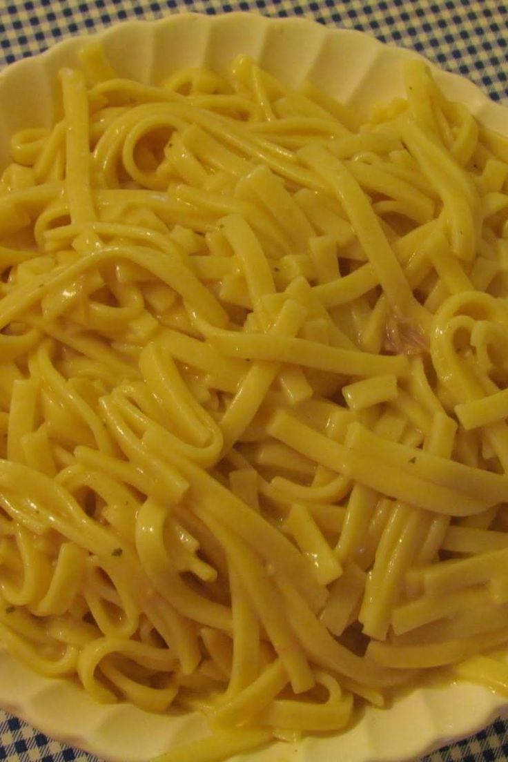 a white bowl filled with pasta on top of a blue and white checkered table cloth