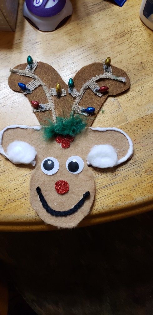 a reindeer head made out of cardboard on a wooden table with other items in the background