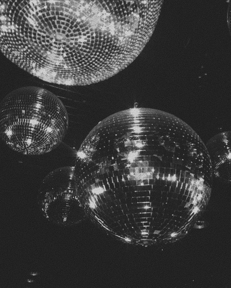 several disco balls hanging from the ceiling in black and white with lights shining on them