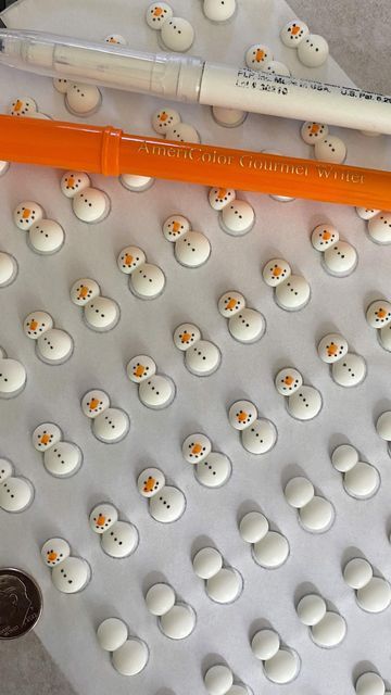 an orange marker sitting on top of a white surface next to some small snowmen