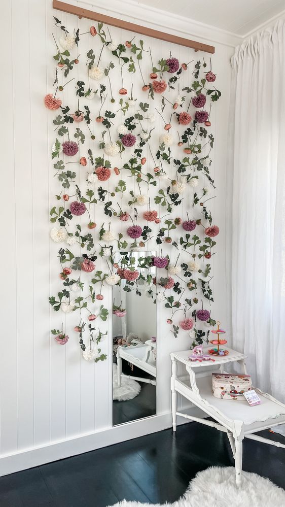 a white room with flowers on the wall and a table in front of it,