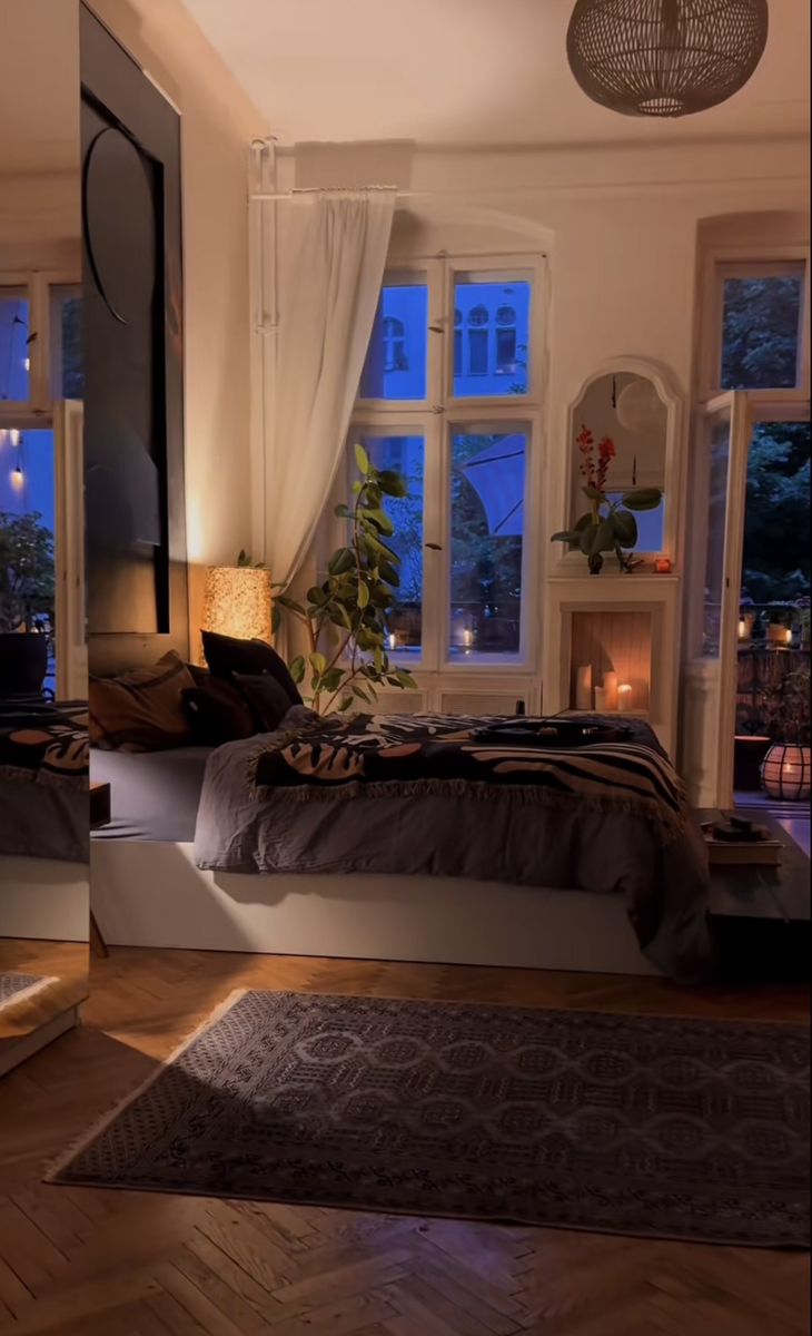 a bed room with a neatly made bed next to two windows and a rug on the floor