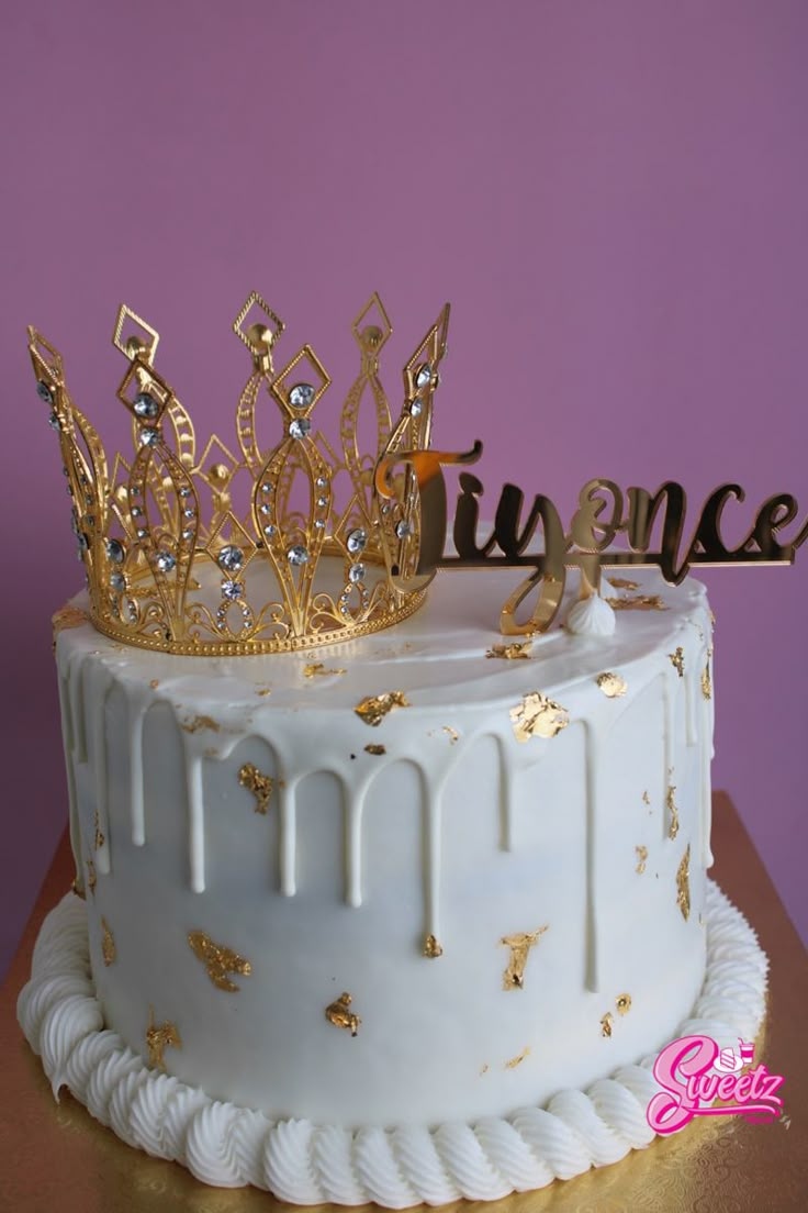 a white cake with gold decorations and a tiara on top