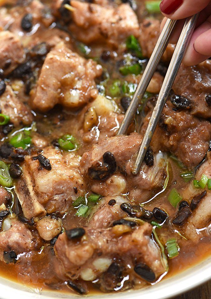 someone is holding chopsticks over a bowl of food with meat and vegetables in it