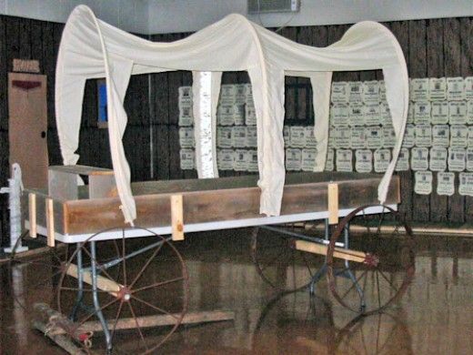 an old fashioned carriage with white drapes on it's sides in a warehouse