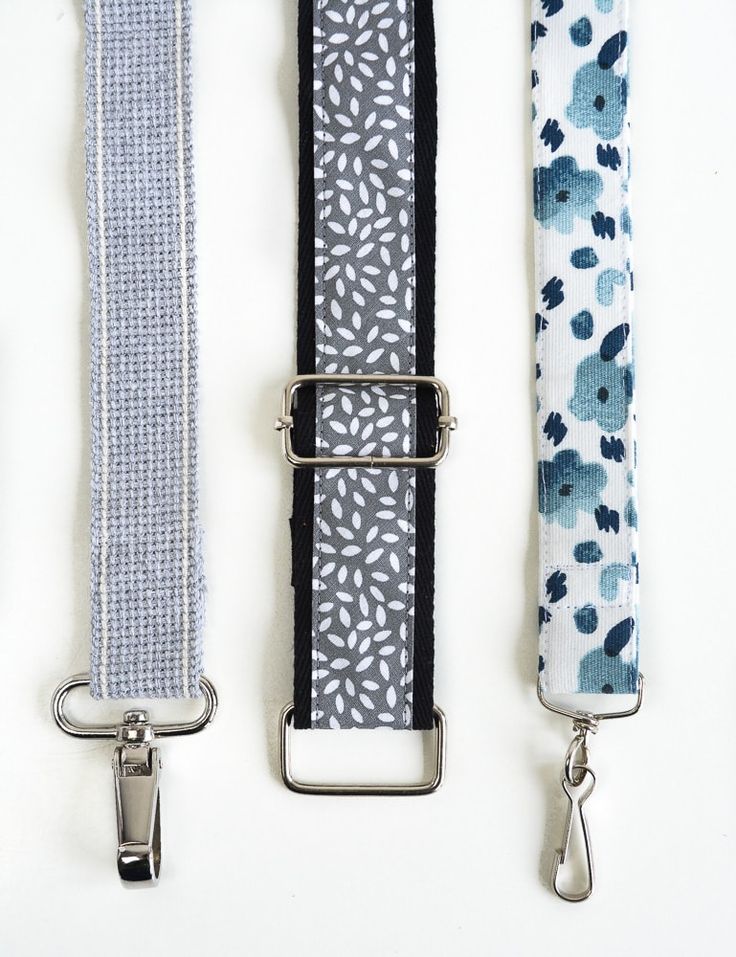 three different colored straps are lined up on a white surface, one is blue and the other is black