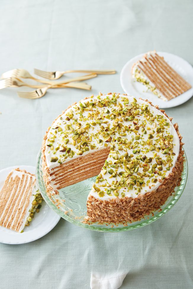 a cake with white frosting and pistachio toppings on a glass platter