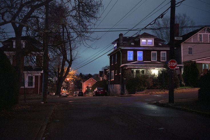 an empty street at night with houses and power lines in the background on a gloomy day