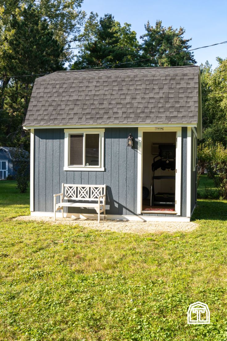 a small gray shed with a white bench