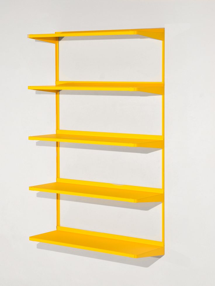 a yellow shelf on the wall with three different shelves in front of it and one is empty