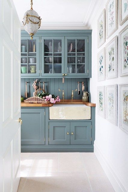 a kitchen with blue cabinets and pictures on the wall above it, along with a chandelier