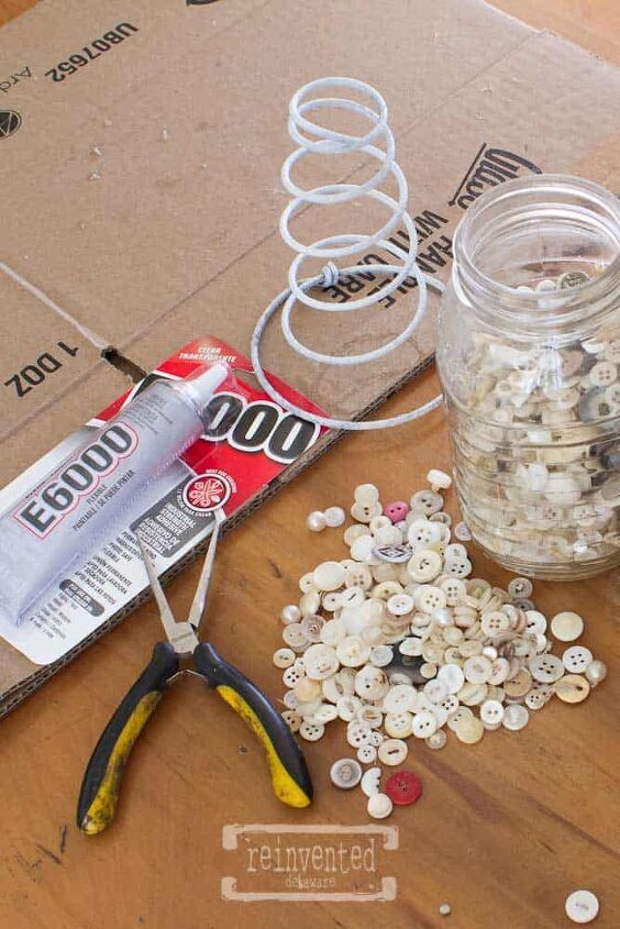 scissors and buttons are sitting on the floor next to a jar filled with coins, glue, and other items