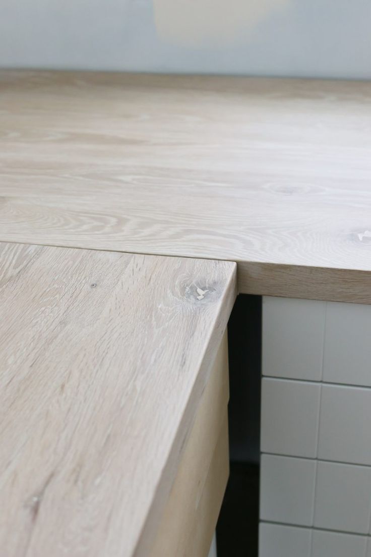 a wooden counter top sitting next to a white tiled wall