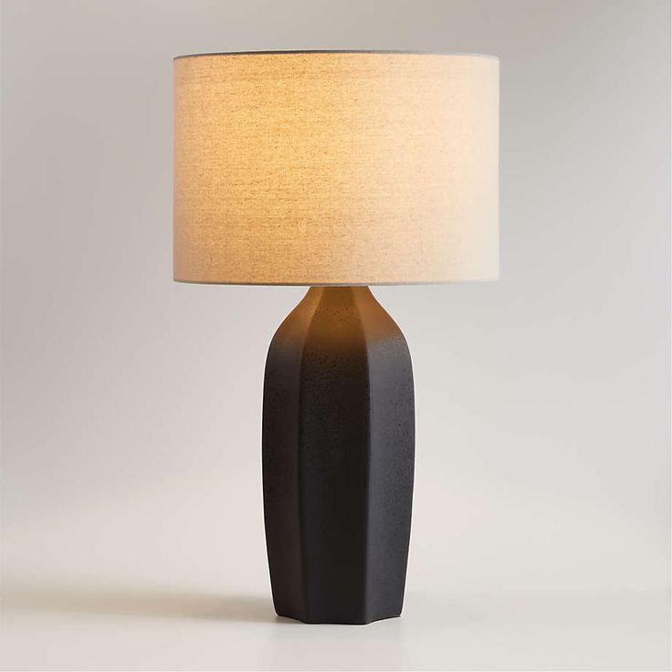 a black table lamp with a white shade on it's base and a beige linen lampshade