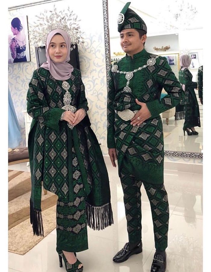 a man and woman dressed in green outfits standing next to each other on the floor