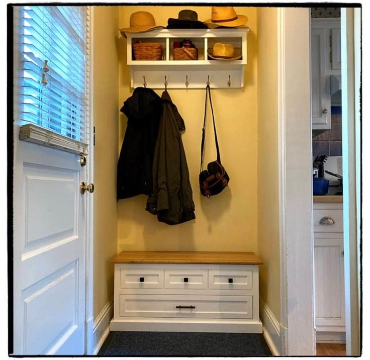 a coat rack with hats and purses hanging from it's sides next to a white door