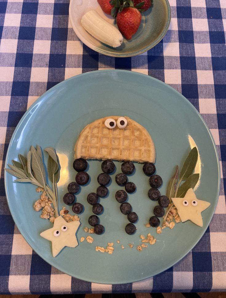 a blue plate topped with waffles and berries on top of a checkered table cloth