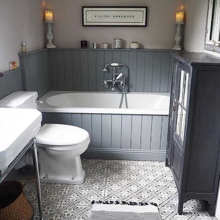 a white toilet sitting next to a bath tub in a bathroom with gray walls and flooring