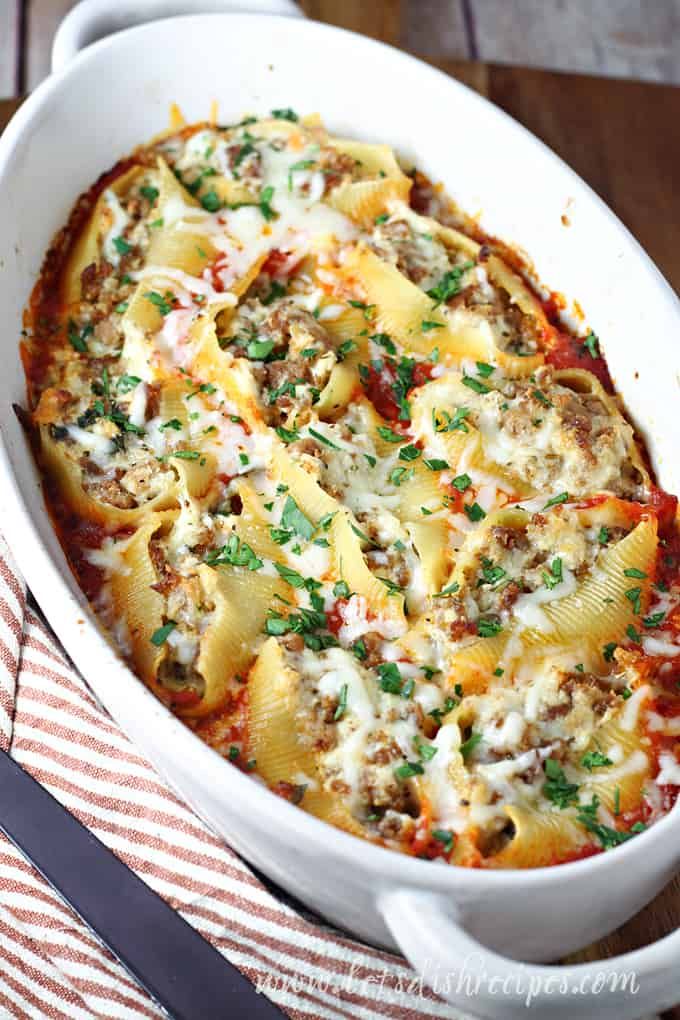 a casserole dish with meat, cheese and sauce in it on a striped cloth