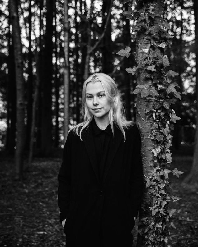 a woman standing next to a tree in the woods