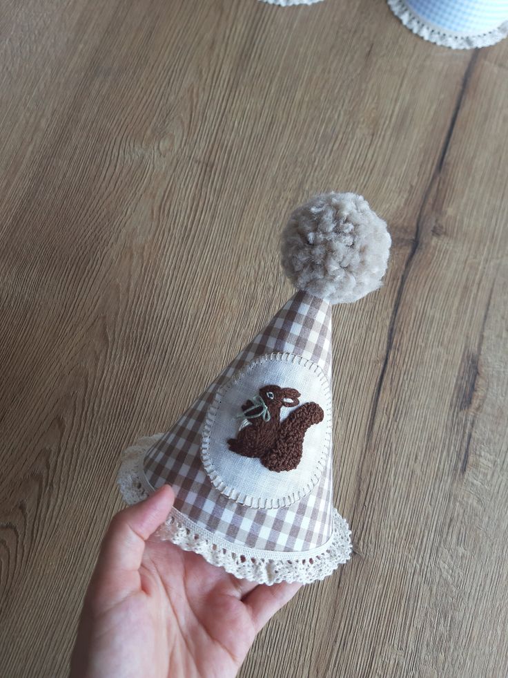 a hand holding a small hat on top of a wooden table