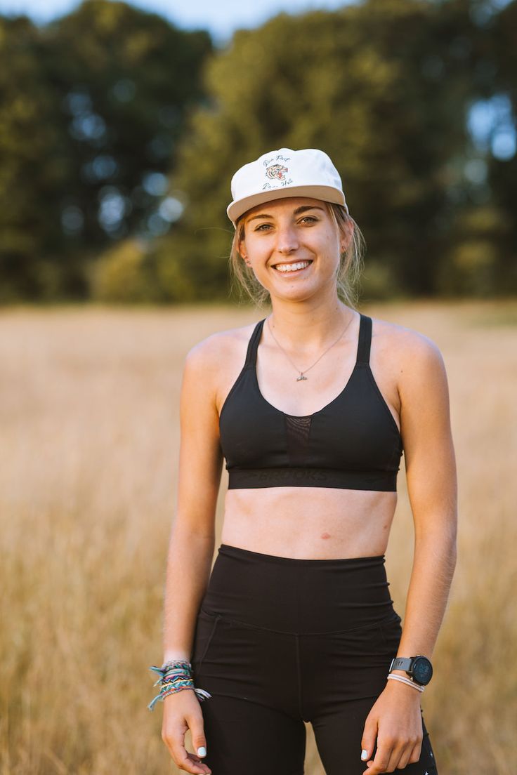 a woman standing in the middle of a field wearing a black sports bra top and leggings