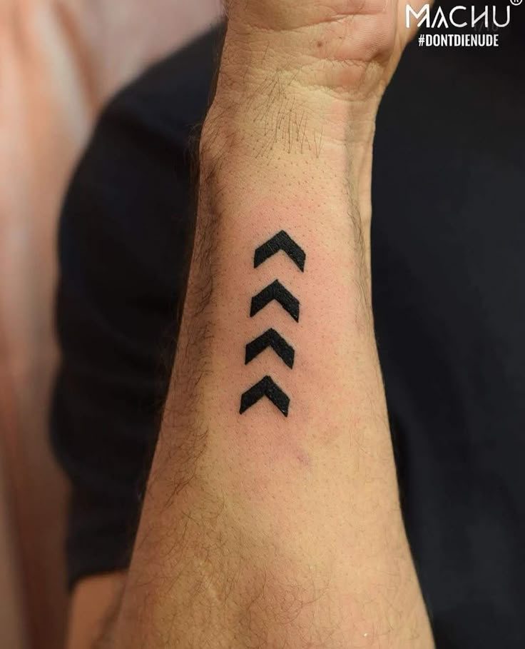 a man's wrist with an arrow tattoo on the left side of his arm