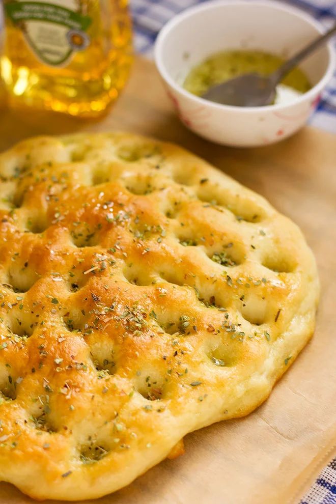 a close up of a pastry on a cutting board with olive oil in the background