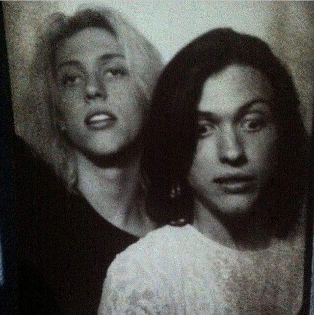 two women standing next to each other in front of a mirror