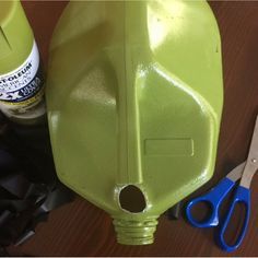 a green plastic bottle sitting on top of a table next to scissors