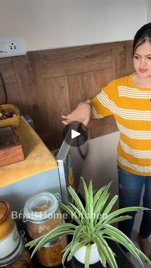 a woman standing in front of a toaster oven next to a potted plant