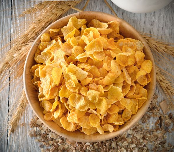 a wooden bowl filled with corn flakes on top of a table