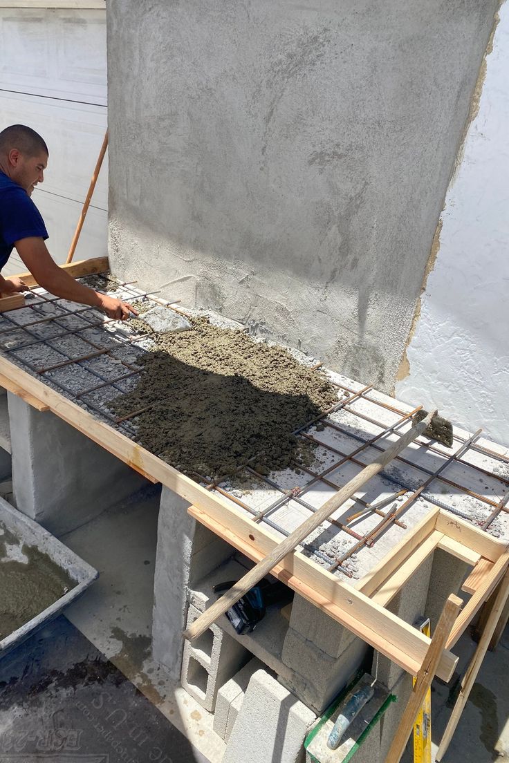 a man laying cement on top of a building