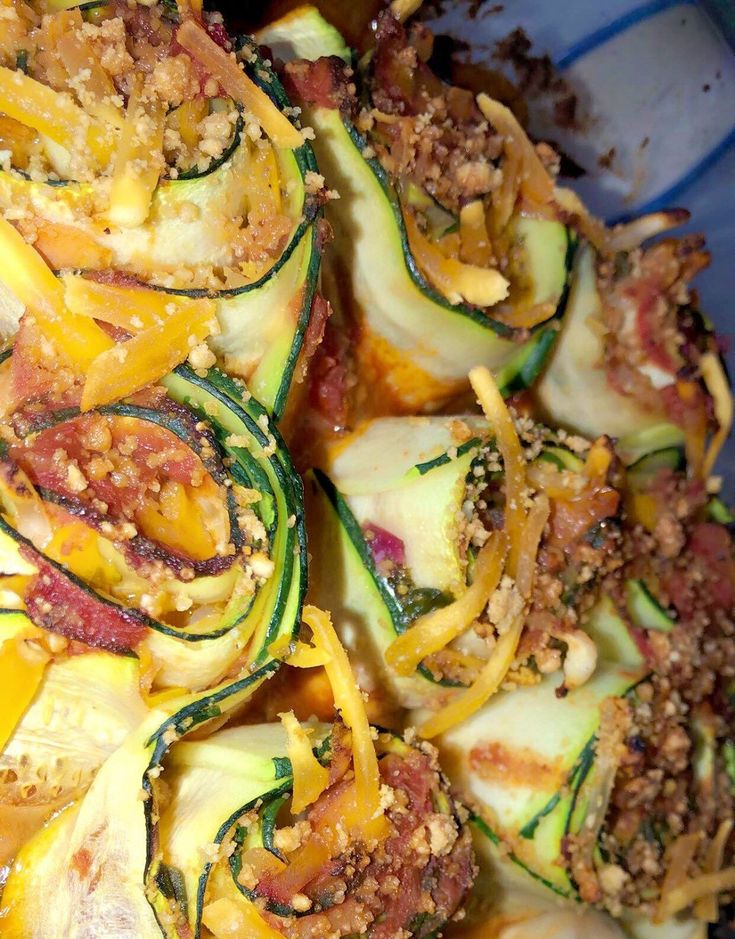 a blue bowl filled with zucchini and other food items on top of it