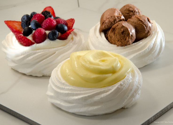 three desserts with whipped cream and fruit on top