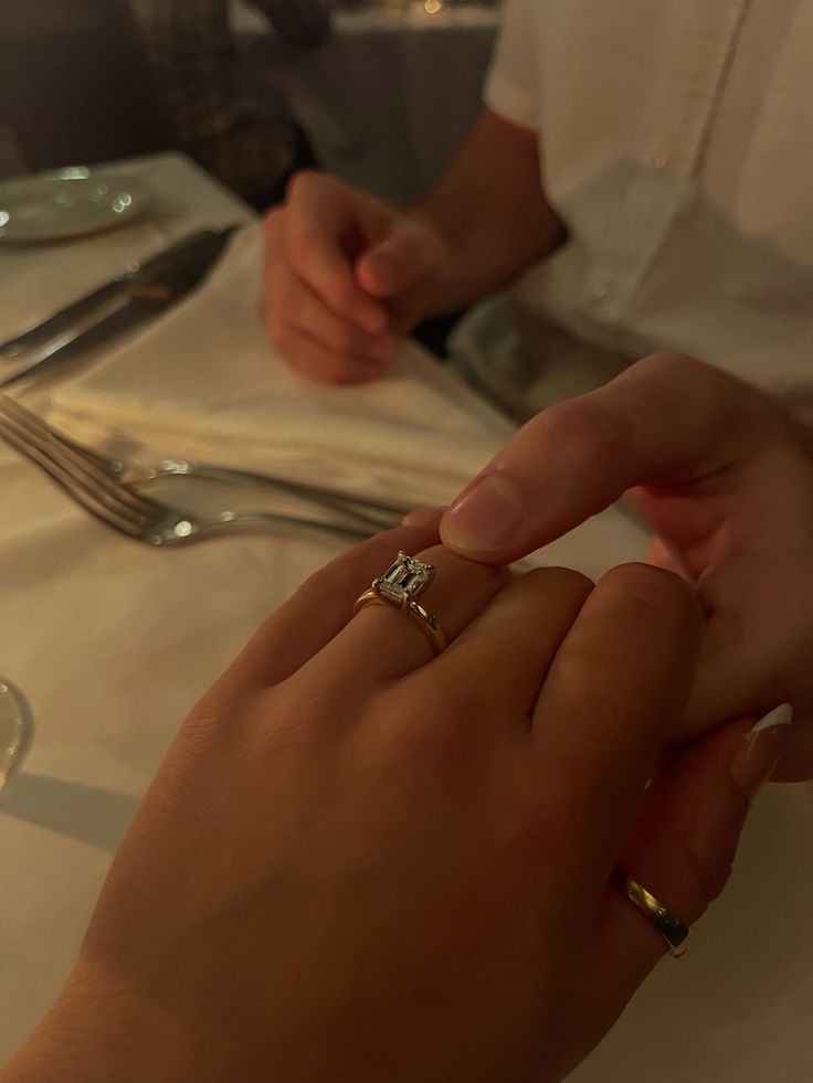 two people holding hands at a table with silverware