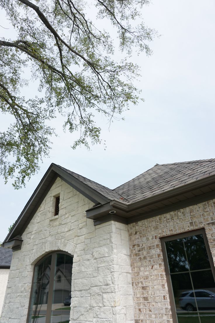 a white brick house with a tree in the front yard