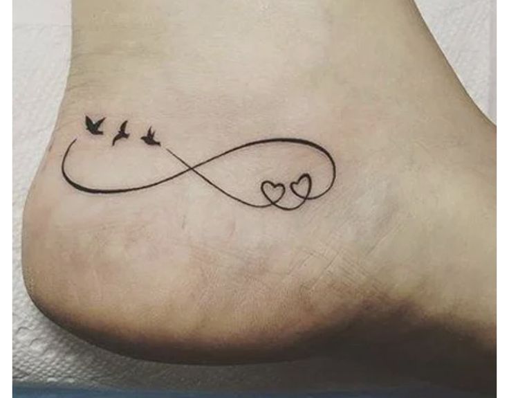 a tattoo on the foot of a woman with two birds flying over it and an infinite love