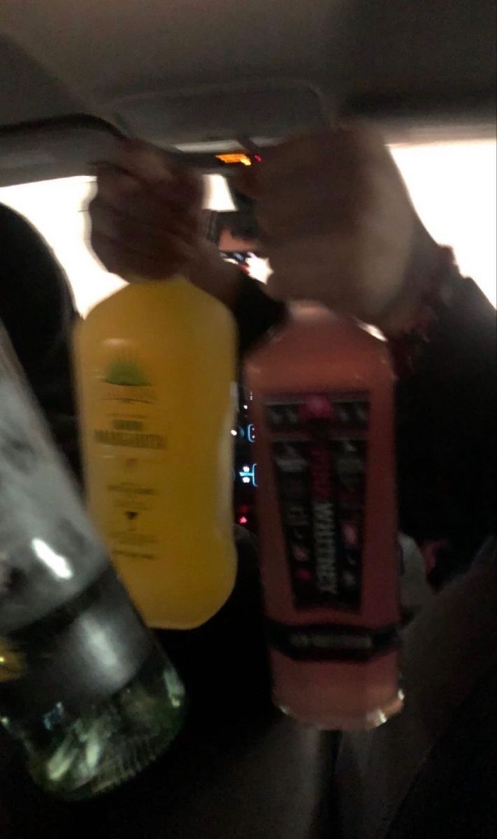 a person holding two bottles in the back of a car