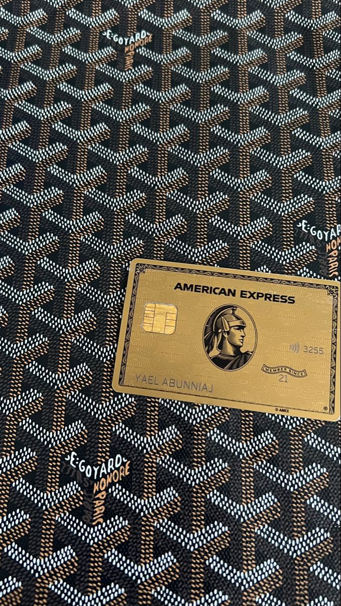 an american express credit card sitting on top of a black and gold patterned table cloth