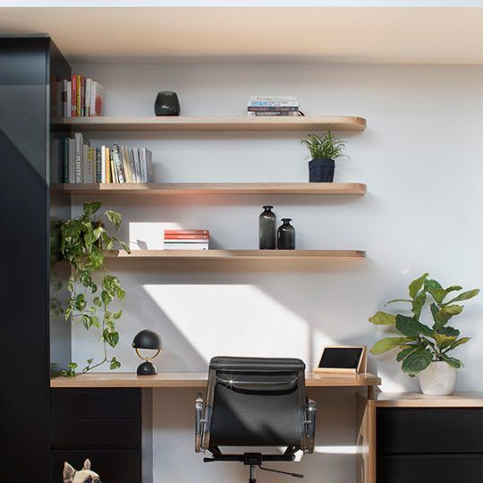 a desk with a chair, bookshelf and plants