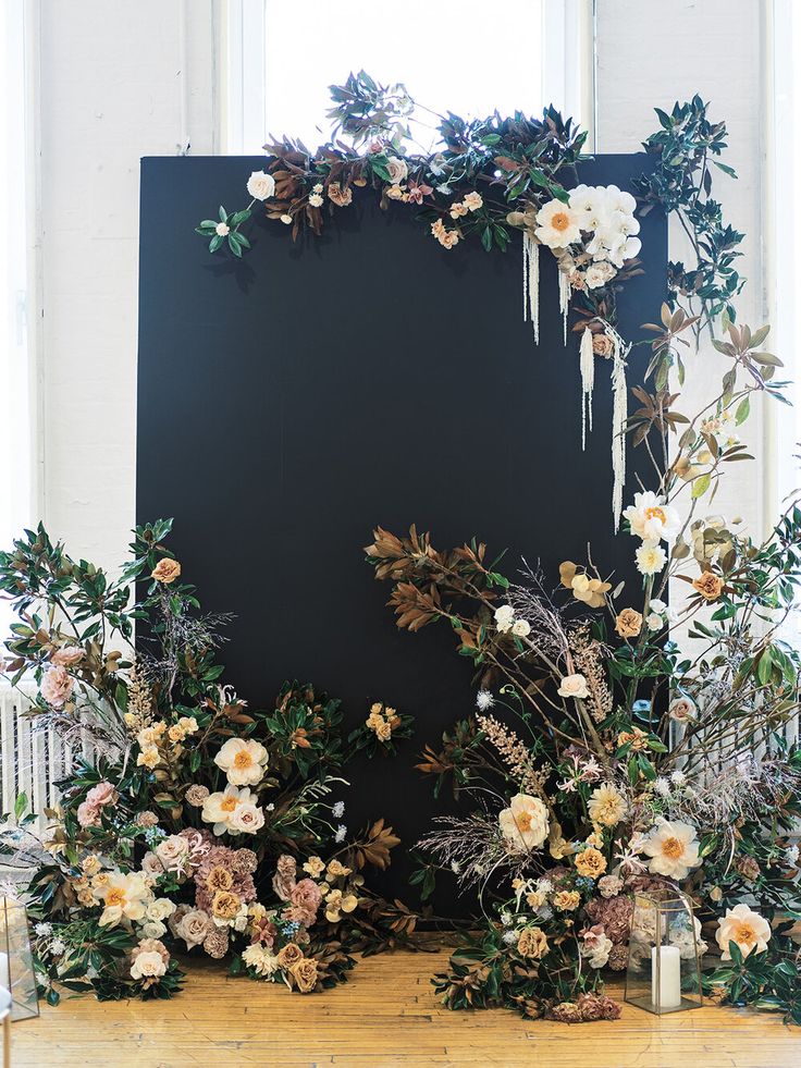 a black backdrop with flowers and greenery