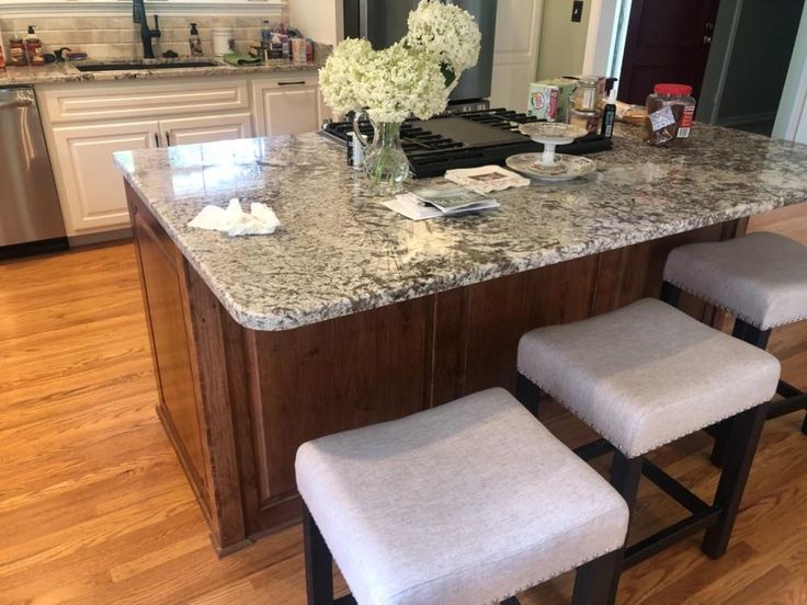 a kitchen island with two stools in front of it and flowers on the counter