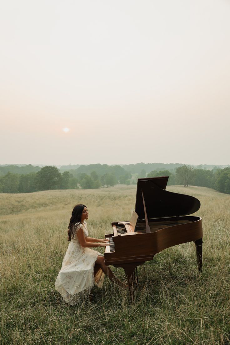 a woman sitting at a piano in a field