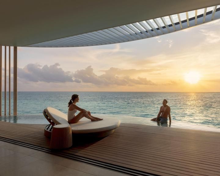 two people sitting on lounge chairs in front of the ocean at sunset or sunrise time