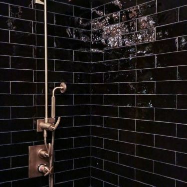 the shower head is on and there are black tiles