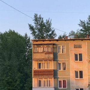 an apartment building with balconies on the second story and trees in the background