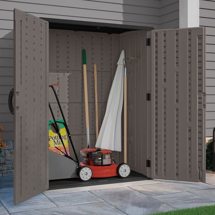 an outdoor storage shed with a lawn mower, umbrella and other items in it